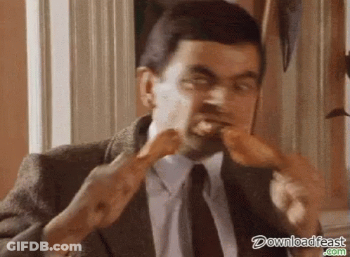 A Man In A Suit And Tie Is Eating A Hot Dog . GIF