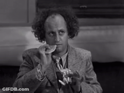 A Man In A Suit And Tie Is Eating A Piece Of Food GIF
