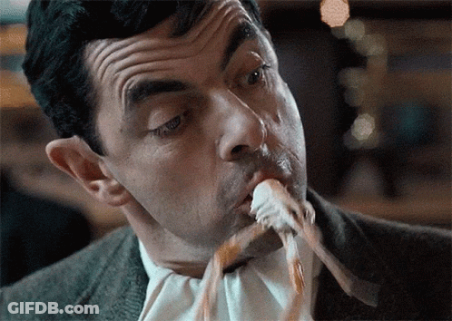 A Man In A Suit And Tie Is Eating A Piece Of Food GIF