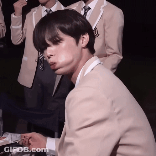 A Man In A Suit And Tie Is Eating Something GIF