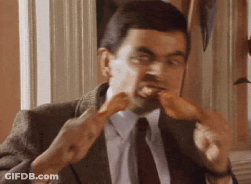 A Man In A Suit And Tie Is Eating Two Chicken Legs . GIF