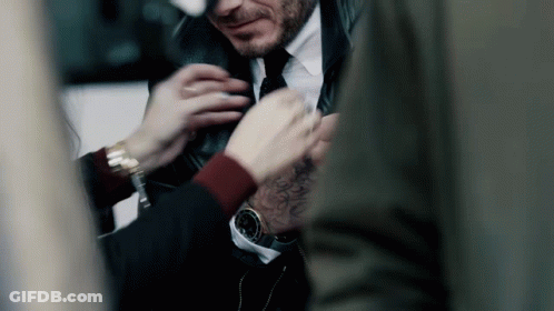 A Man In A Suit And Tie Is Getting His Tie Adjusted GIF