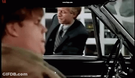 A Man In A Suit And Tie Is Getting Out Of A Car While Another Man Looks On . GIF