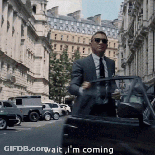 A Man In A Suit And Tie Is Getting Out Of A Car With The Words " Wait I 'M Coming " Below Him GIF