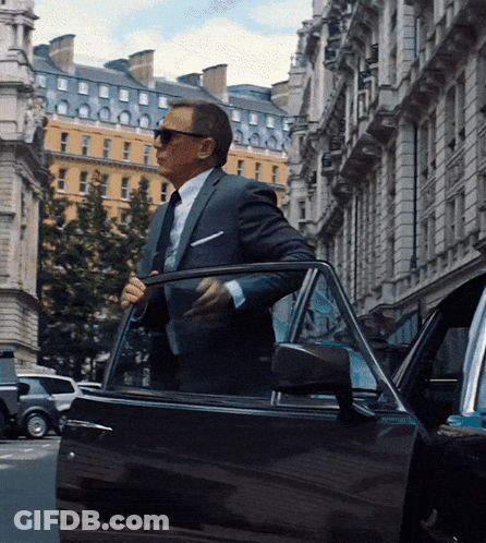 A Man In A Suit And Tie Is Getting Out Of His Car GIF