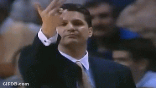 A Man In A Suit And Tie Is Giving A Middle Finger To The Camera . GIF