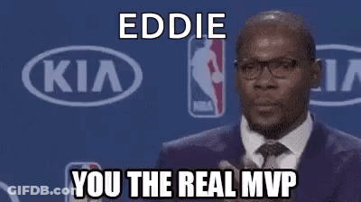 A Man In A Suit And Tie Is Giving A Speech At A Basketball Game . GIF