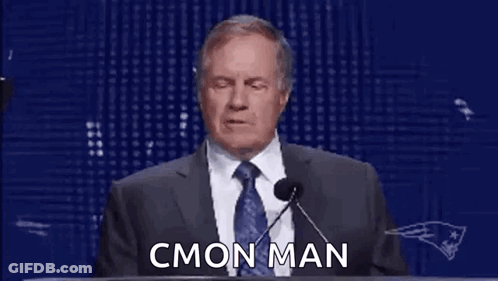 A Man In A Suit And Tie Is Giving A Speech At A Podium With Rings On His Hands . GIF