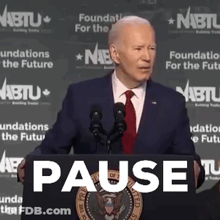 Man In Suit And Tie At Podium With Pause Sign GIF