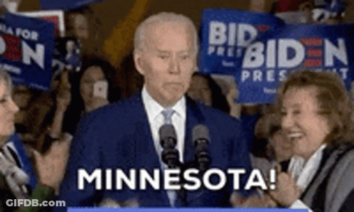 A Man In A Suit And Tie Is Giving A Speech In Front Of A Crowd And Says Minnesota GIF