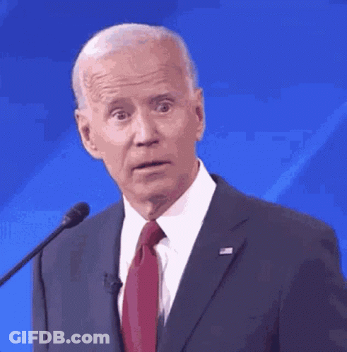 A Man In A Suit And Tie Is Giving A Speech In Front Of A Microphone . GIF