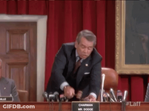 A Man In A Suit And Tie Is Giving A Speech In Front Of A Microphone . GIF