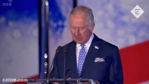 A Man In A Suit And Tie Is Giving A Speech In Front Of Microphones . GIF