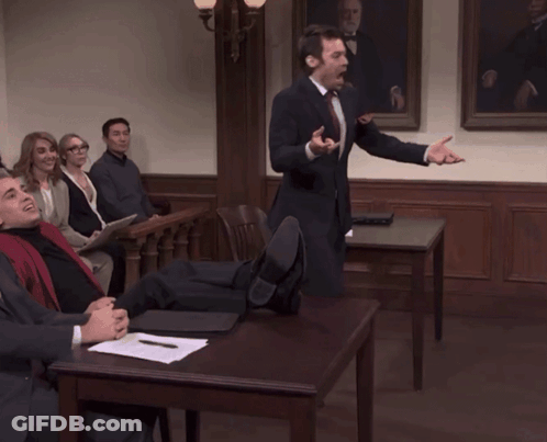 A Man In A Suit And Tie Is Giving A Speech To A Group Of People GIF