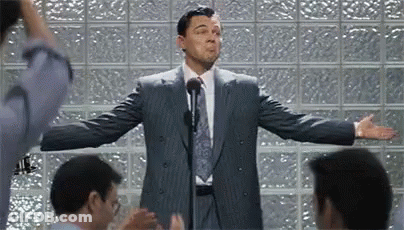 A Man In A Suit And Tie Is Giving A Speech To A Group Of People . GIF