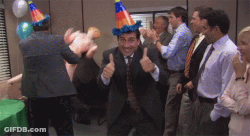 A Man In A Suit And Tie Is Giving A Thumbs Up At A Party While A Group Of People Applaud . GIF