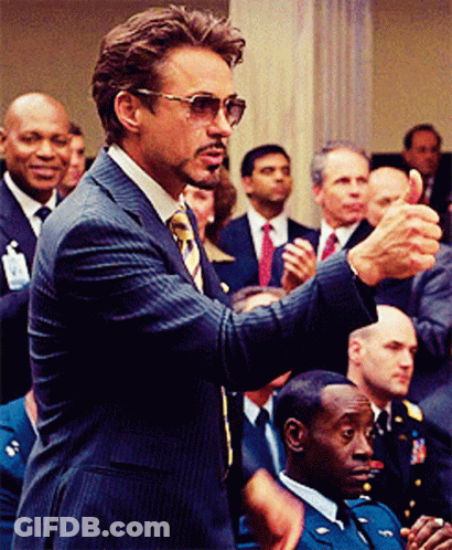 A Man In A Suit And Tie Is Giving A Thumbs Up In Front Of A Crowd GIF