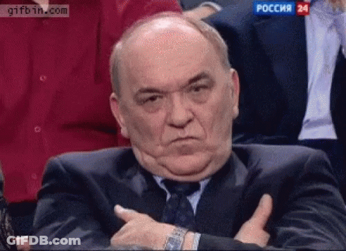 A Man In A Suit And Tie Is Giving A Thumbs Up Sign While Sitting In A Audience . GIF