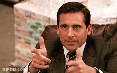 A Man In A Suit And Tie Is Giving A Thumbs Up While Sitting In A Chair . GIF