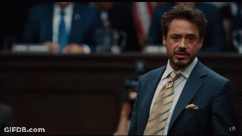 A Man In A Suit And Tie Is Giving The Peace Sign GIF