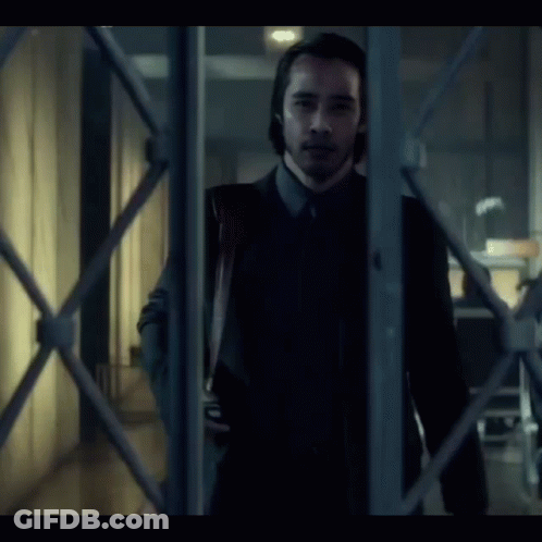 A Man In A Suit And Tie Is Holding A Bloody Knife In His Hand GIF