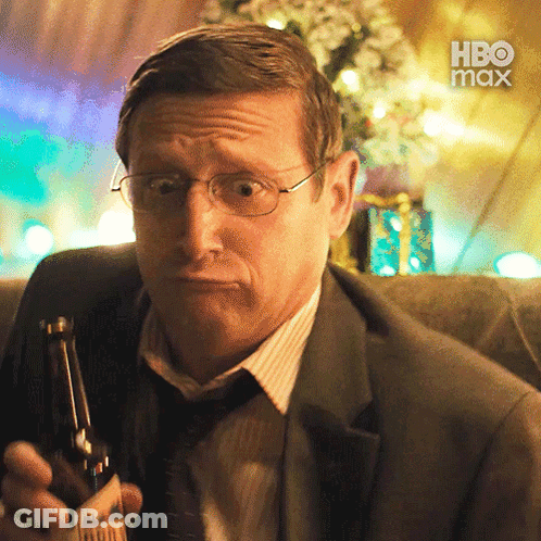 A Man In A Suit And Tie Is Holding A Bottle Of Beer With A Hbo Max Logo In The Background GIF