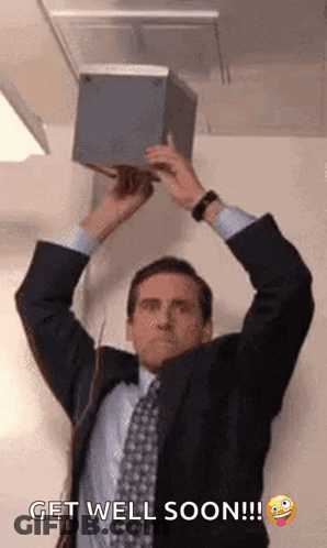 A Man In A Suit And Tie Is Holding A Box In His Hands Over His Head . GIF