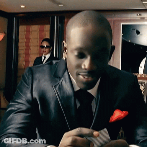 A Man In A Suit And Tie Is Holding A Card GIF