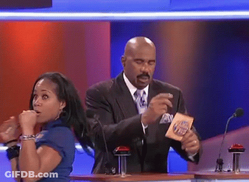A Man In A Suit And Tie Is Holding A Card That Says ' I 'M Hungry ' On It GIF