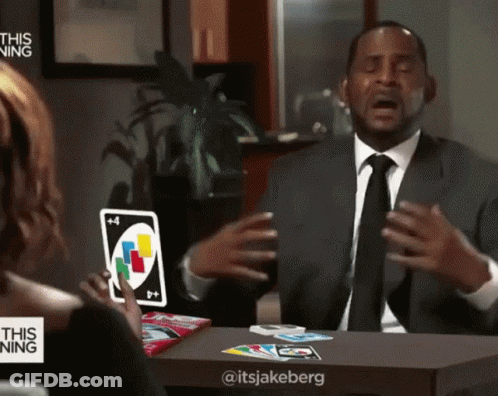 A Man In A Suit And Tie Is Holding A Card With The Number 4 On It GIF