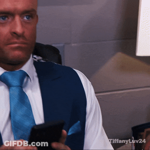 A Man In A Suit And Tie Is Holding A Cell Phone With Tiffany Liv24 Written On The Bottom GIF
