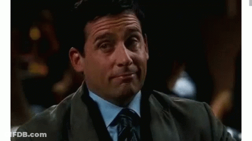 A Man In A Suit And Tie Is Holding A Drink In His Hand And Making A Funny Face . GIF