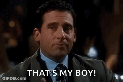 A Man In A Suit And Tie Is Holding A Drink In His Hand And Saying `` That 'S My Boy '' . GIF