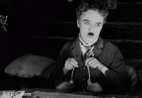 A Man In A Suit And Tie Is Holding A Fork In His Mouth GIF