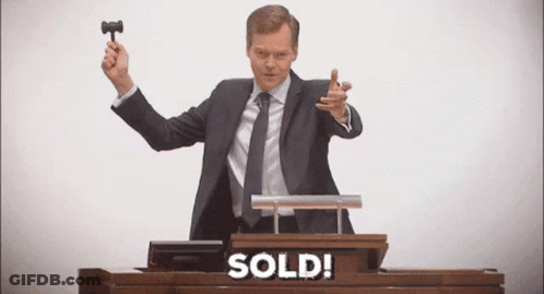 A Man In A Suit And Tie Is Holding A Gavel At An Auction . GIF