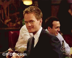 A Man In A Suit And Tie Is Holding A Glass In His Hand GIF