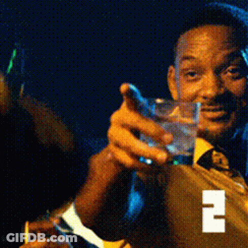 A Man In A Suit And Tie Is Holding A Glass Of Water And A Cigarette GIF