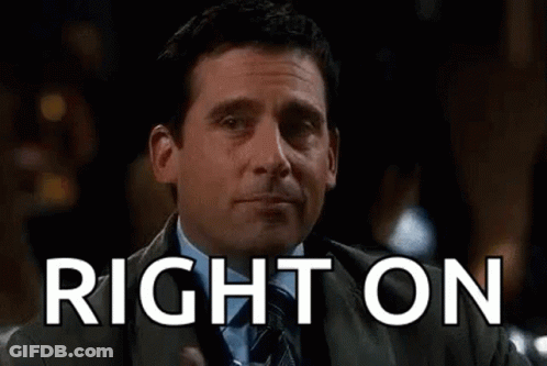 A Man In A Suit And Tie Is Holding A Glass Of Whiskey And Pointing At It . GIF