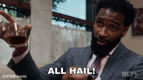 A Man In A Suit And Tie Is Holding A Glass Of Whiskey And Says All Hail GIF