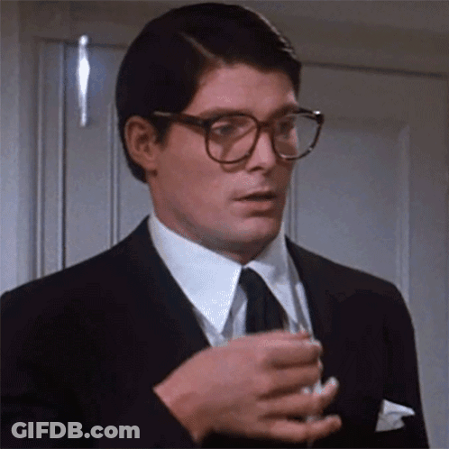 A Man In A Suit And Tie Is Holding A Glass Of Wine GIF