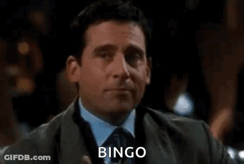 A Man In A Suit And Tie Is Holding A Glass Of Wine And Saying `` Bingo '' . GIF