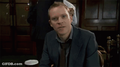 A Man In A Suit And Tie Is Holding A Glass Of Wine GIF