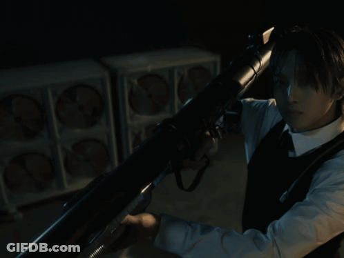 A Man In A Suit And Tie Is Holding A Gun In His Hand GIF