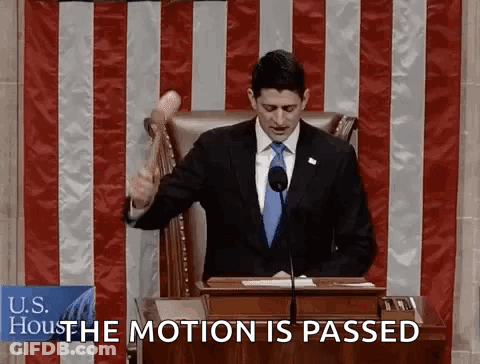 A Man In A Suit And Tie Is Holding A Hammer In Front Of A Podium And Says " The Motion Is Passed " GIF