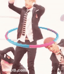 A Man In A Suit And Tie Is Holding A Hula Hoop Around His Waist . GIF
