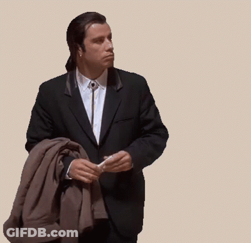 A Man In A Suit And Tie Is Holding A Jacket GIF