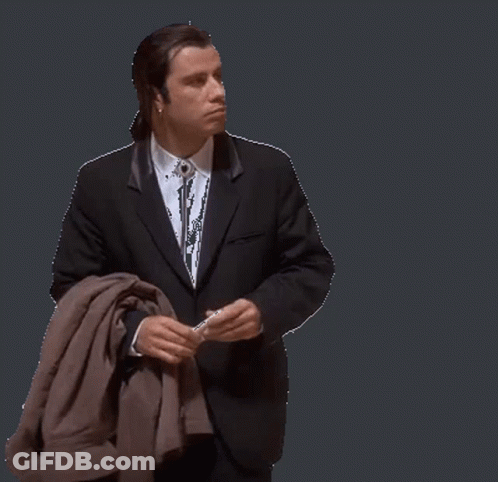 A Man In A Suit And Tie Is Holding A Jacket GIF