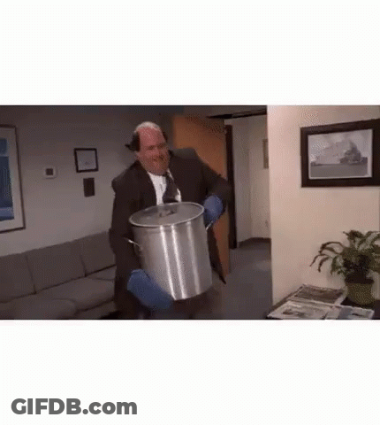 A Man In A Suit And Tie Is Holding A Large Pot . GIF