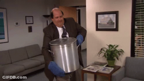 A Man In A Suit And Tie Is Holding A Large Pot In A Waiting Room GIF