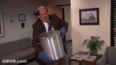 A Man In A Suit And Tie Is Holding A Large Pot . GIF